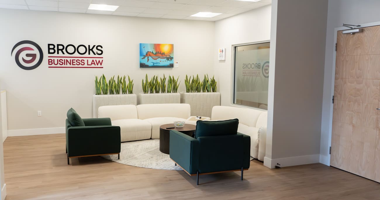 The waiting area at Brooks Business Law: a cream sofa and two green armchairs under the firm's sign.